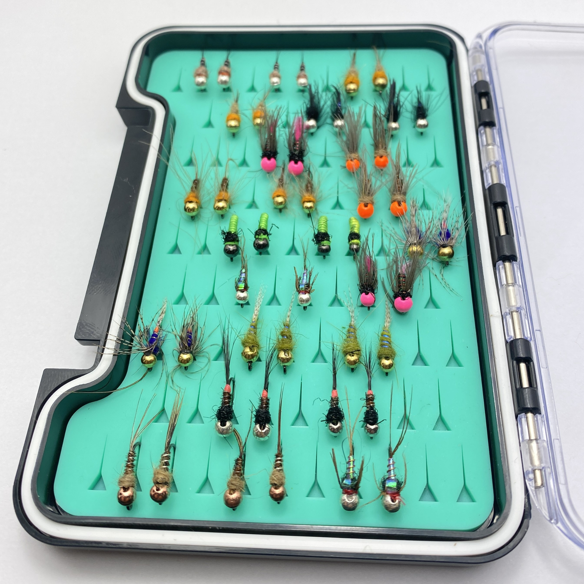 Assorted fishing lures in a green case on a white background