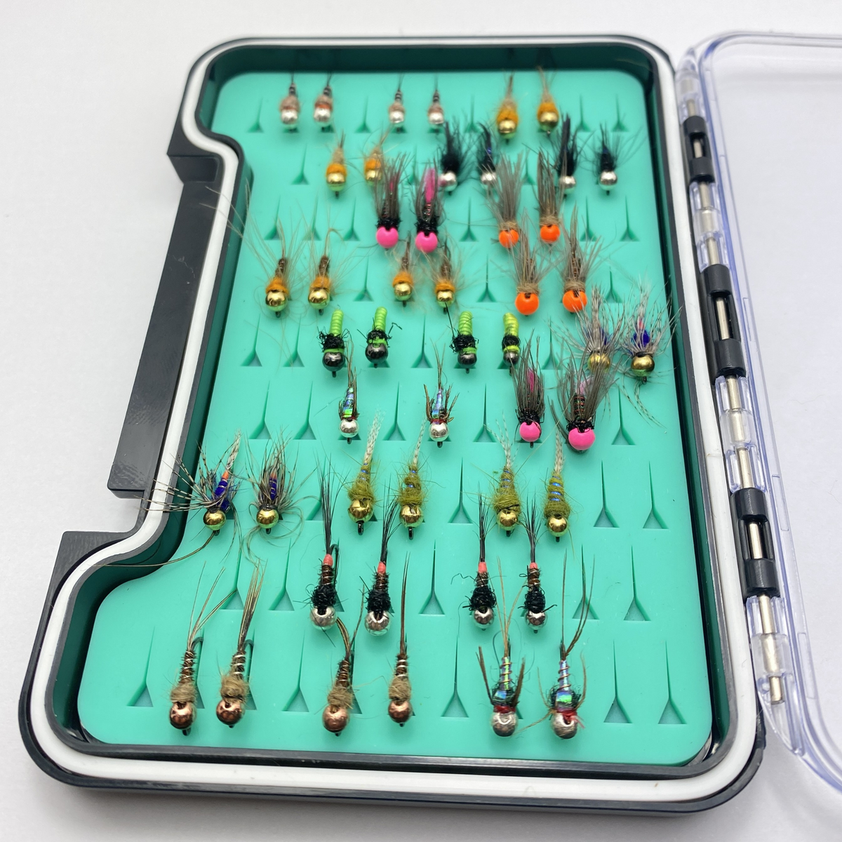 Assorted fishing lures in a green case on a white background
