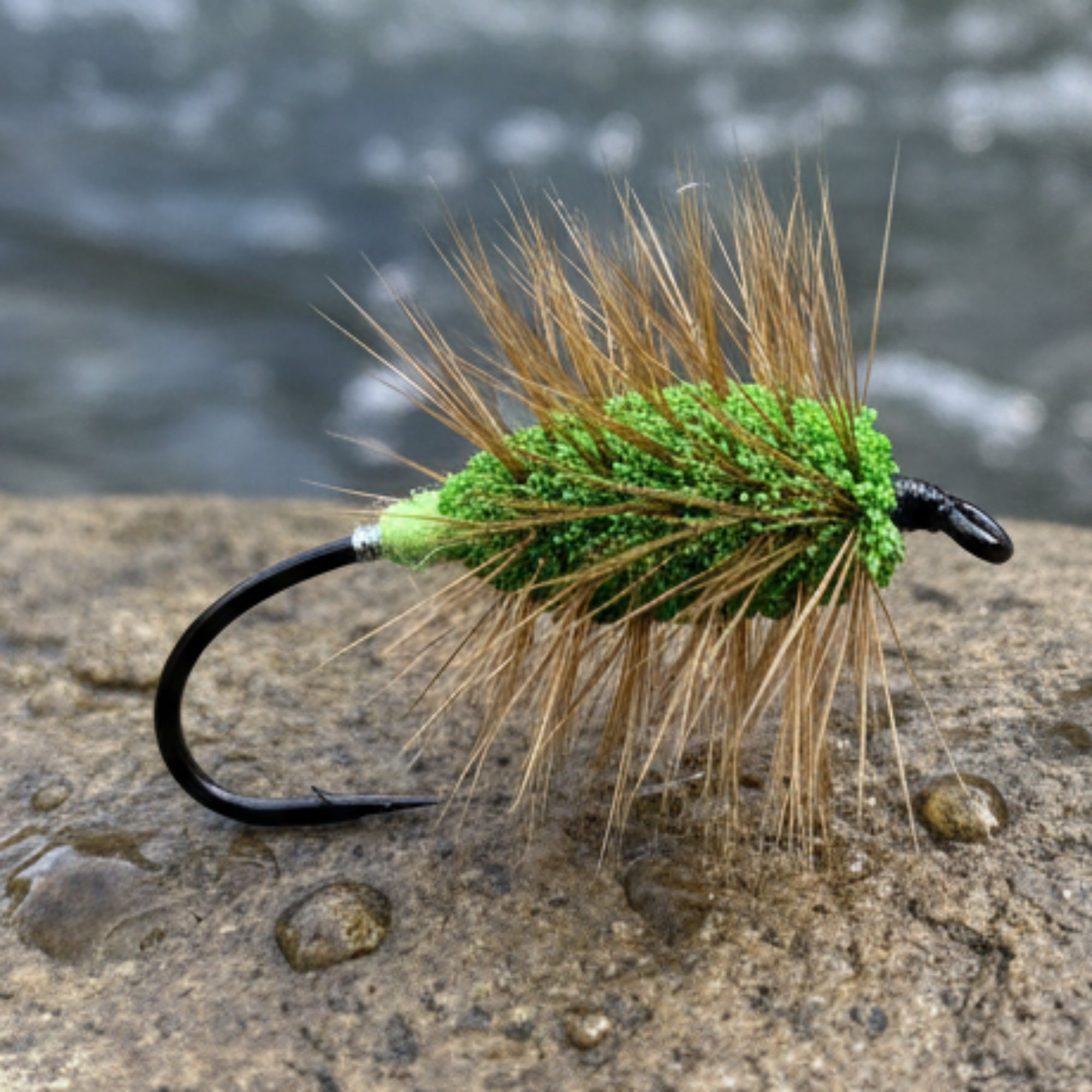 Fishing fly with green body and brown hair on a white background