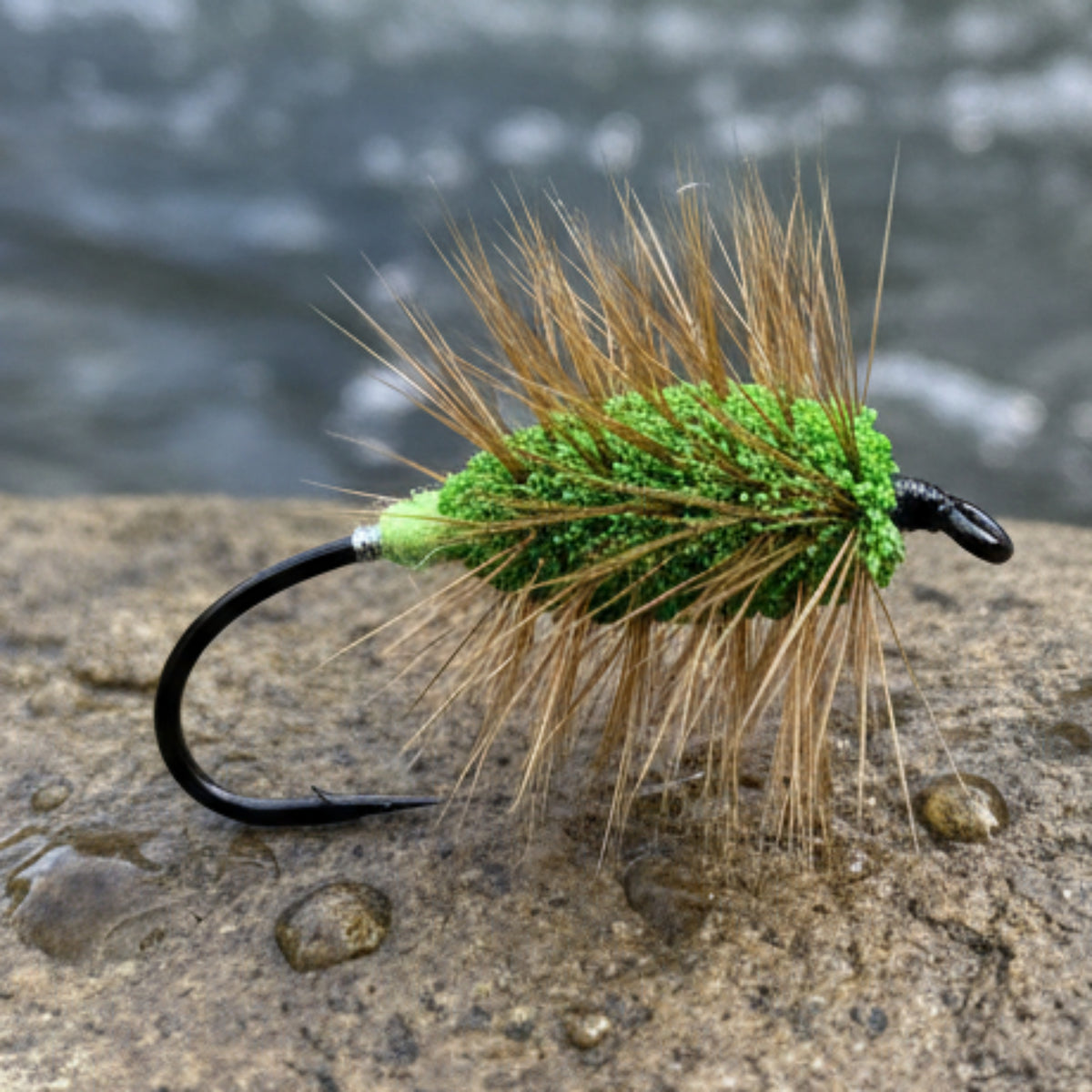 Fishing fly with green body and brown hair on a white background