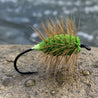 Fishing fly with green body and brown hair on a white background
