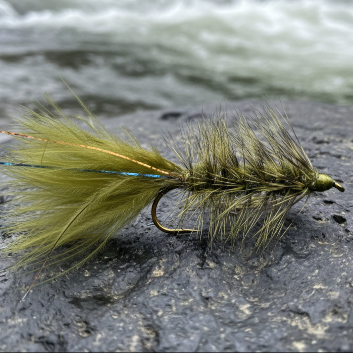 Fishing fly with green and brown feathers on a white grid background