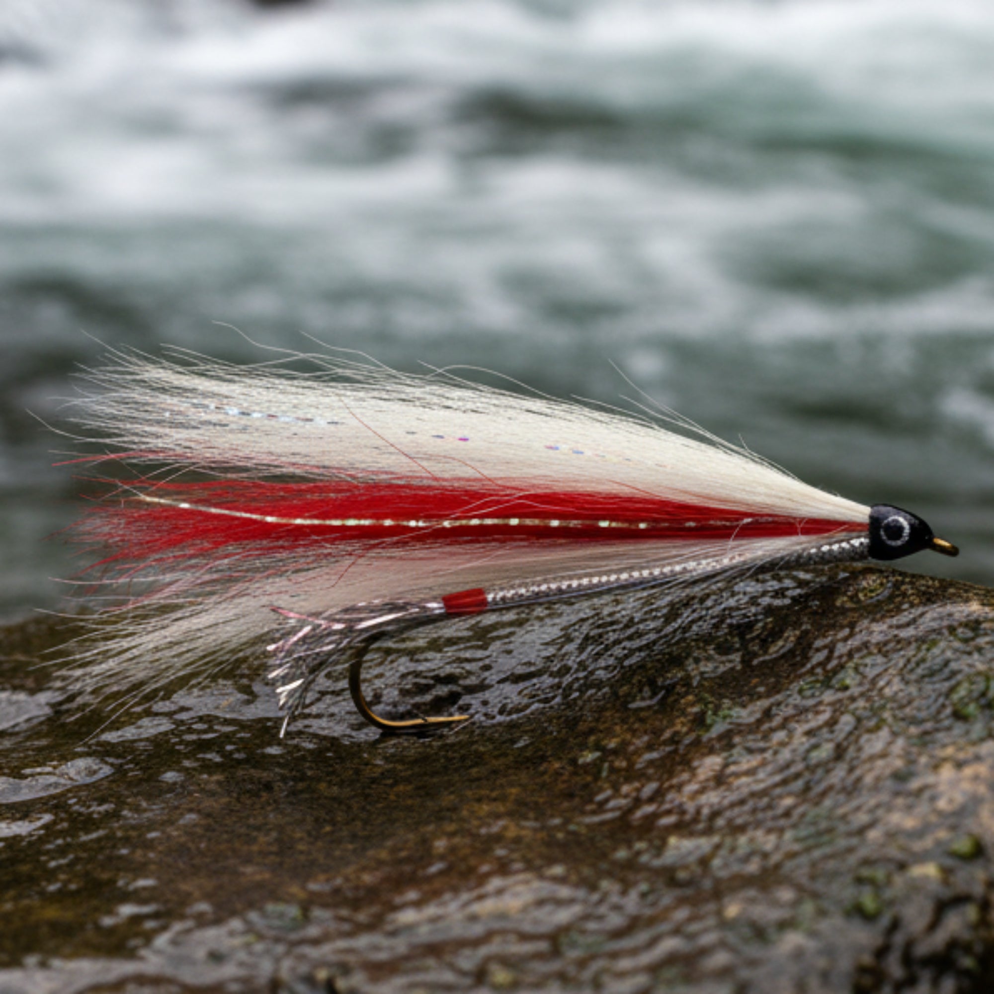 Fishing lure with red and white feathers on a light gray background