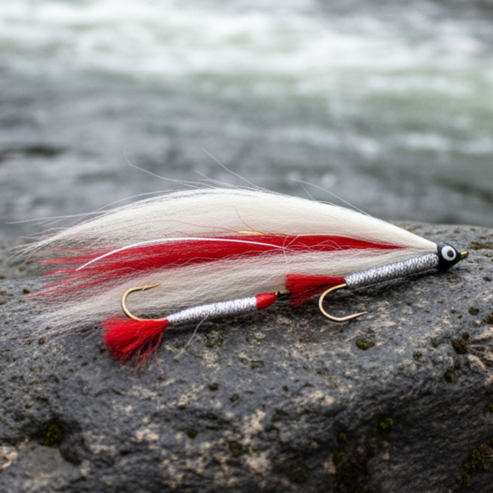 Fishing lure with red and white feathers on a light gray background
