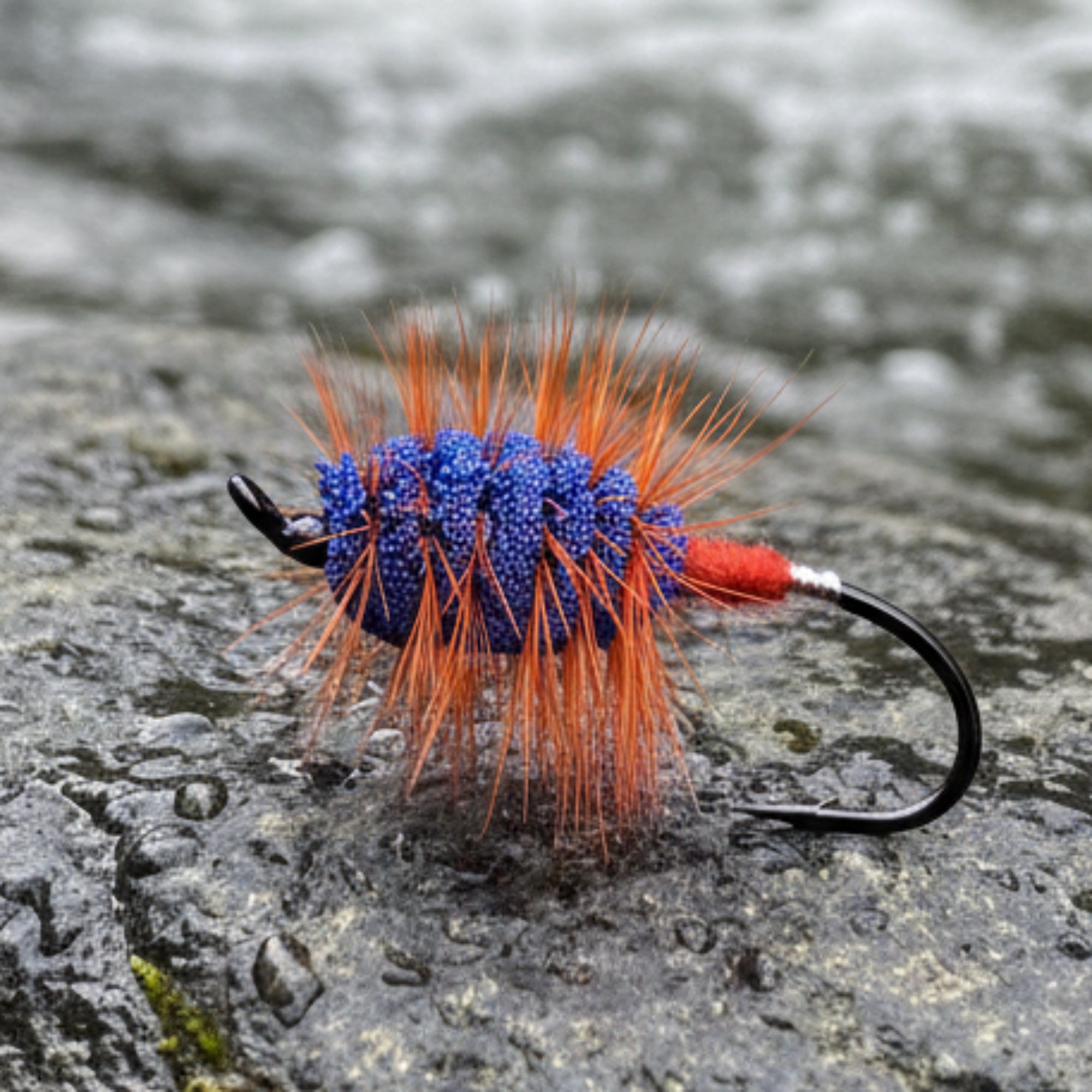 Fishing lure with orange and blue body on a white tiled background