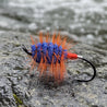 Fishing lure with orange and blue body on a white tiled background