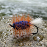 Fishing fly with orange and blue body on a white tiled background