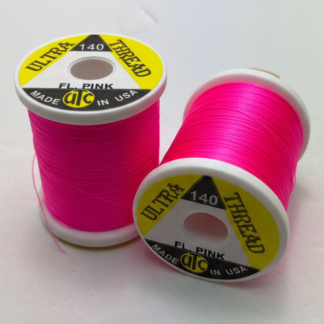 Two spools of bright pink thread labeled ULTRA THREAD 140 FLYWEave, stacked on a plain white surface.