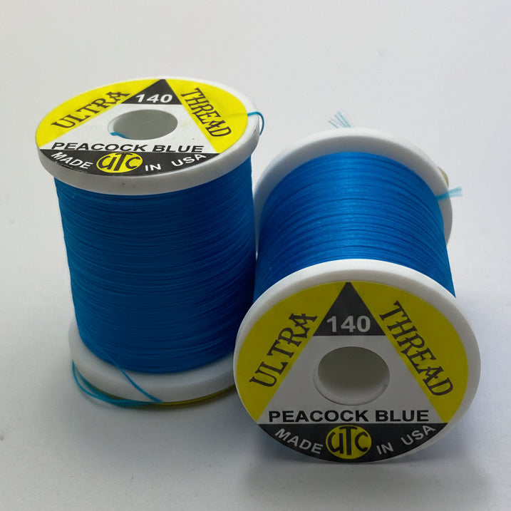 2 spools of UTC140 fly tying thread in Peacock Blue on a white background