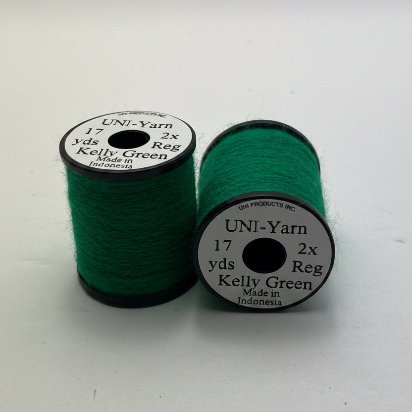 Two spools of UNI-Yarn Kelly Green Reg weight embroidery thread on a plain white background.