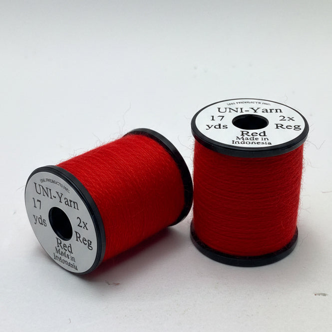 Two spools of red thread on a white background