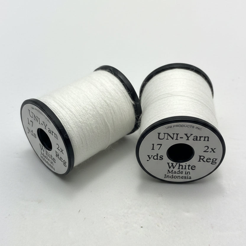 Two spools of white thread labeled 'UNI-Yarn' on a light gray background