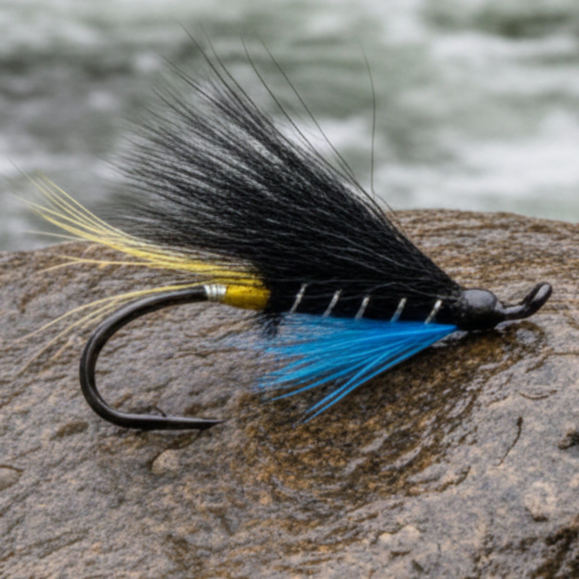 Fishing fly with black and blue feathers on a white background