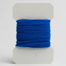 Blue thread on a white spool against a light gray background