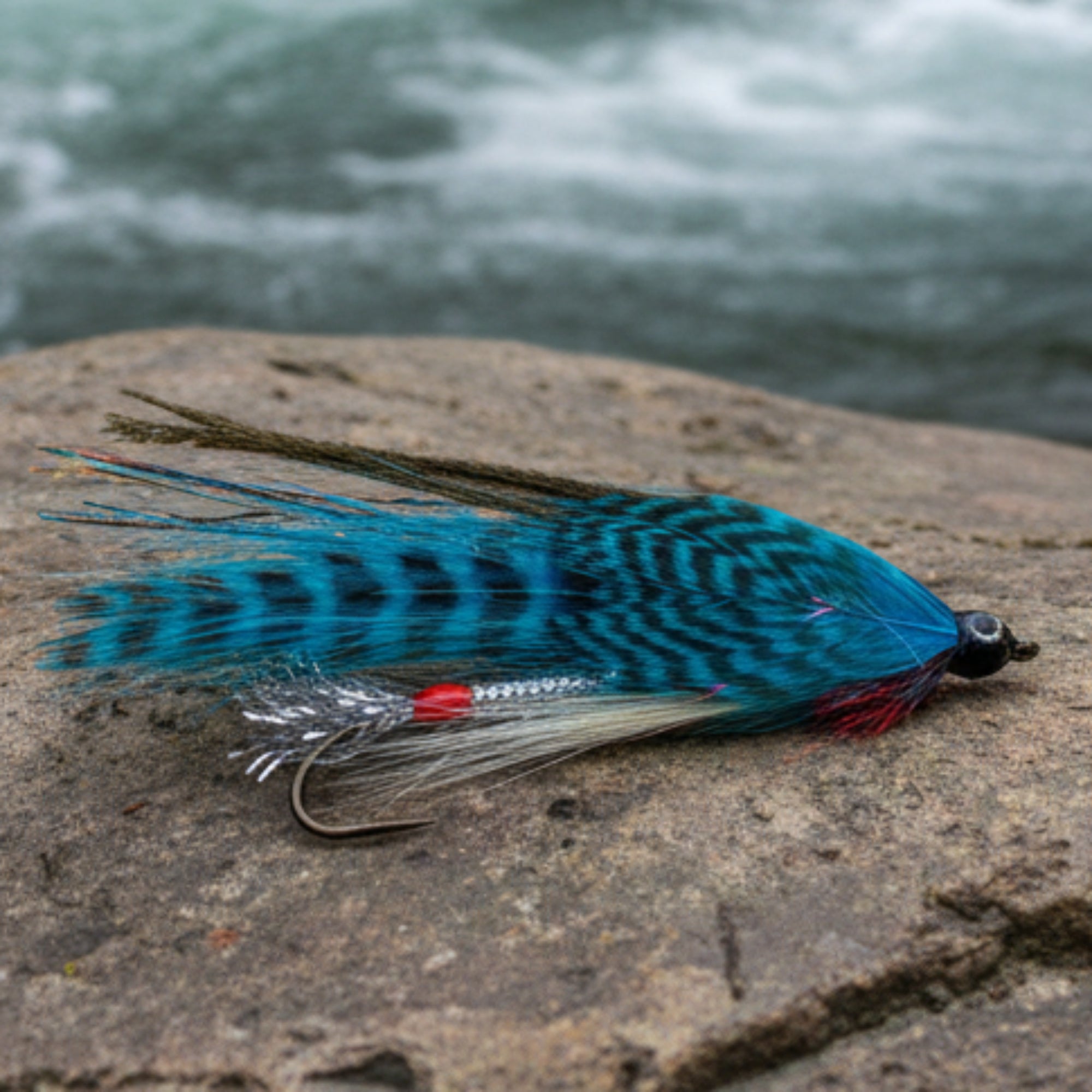 Blue fishing lure with black patterns on a white background