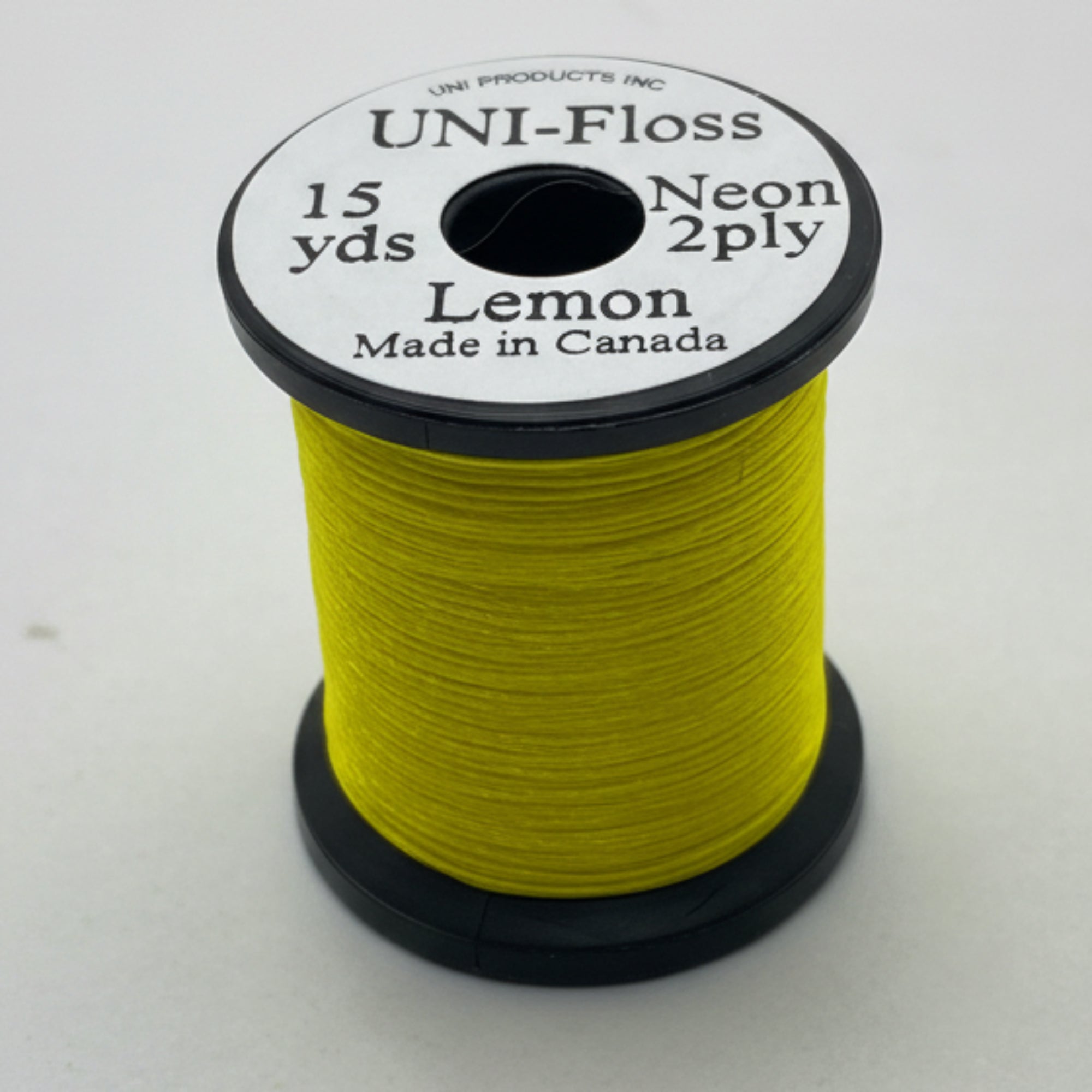 Spool of yellow thread with black and white label on a white background