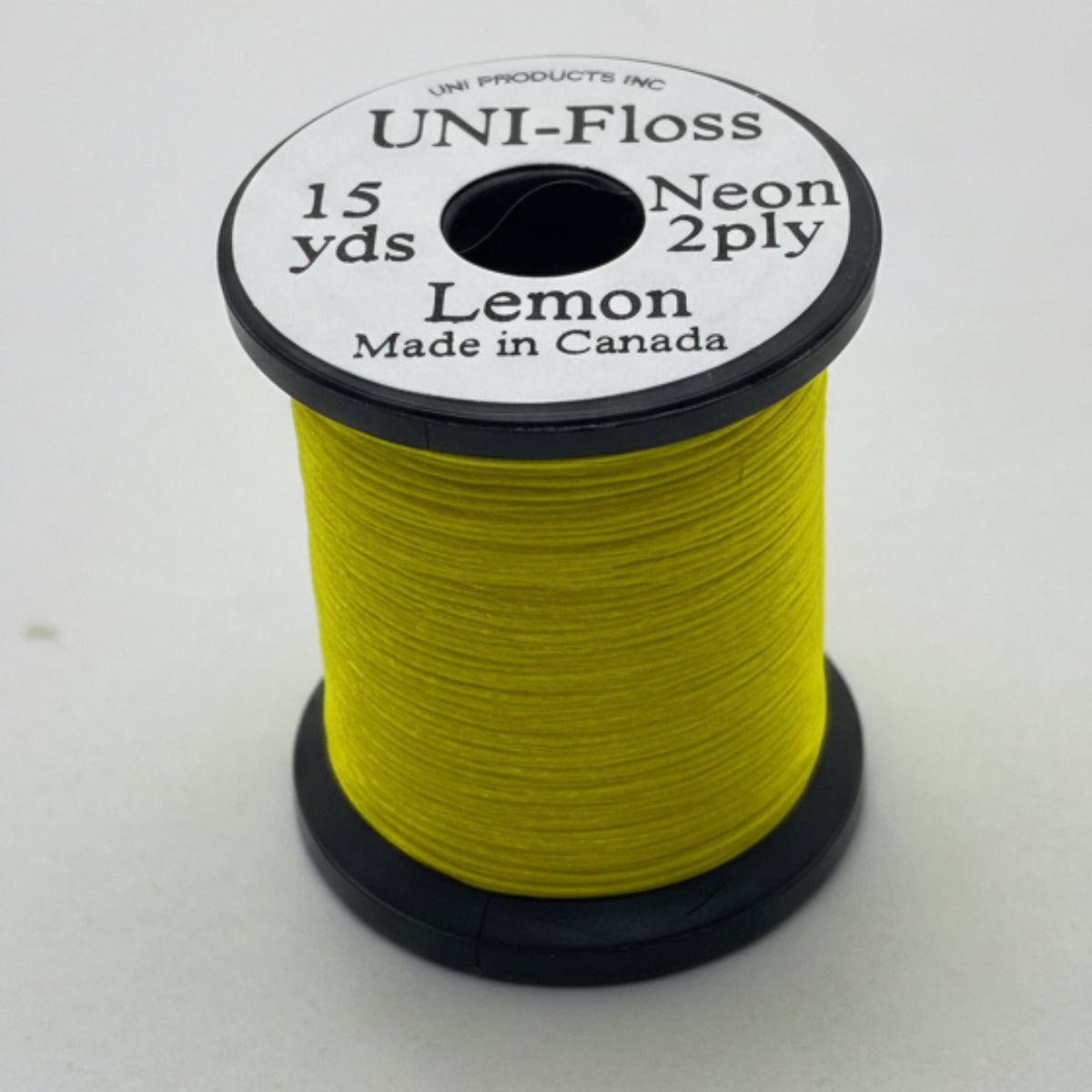 Spool of yellow thread with black and white label on a white background
