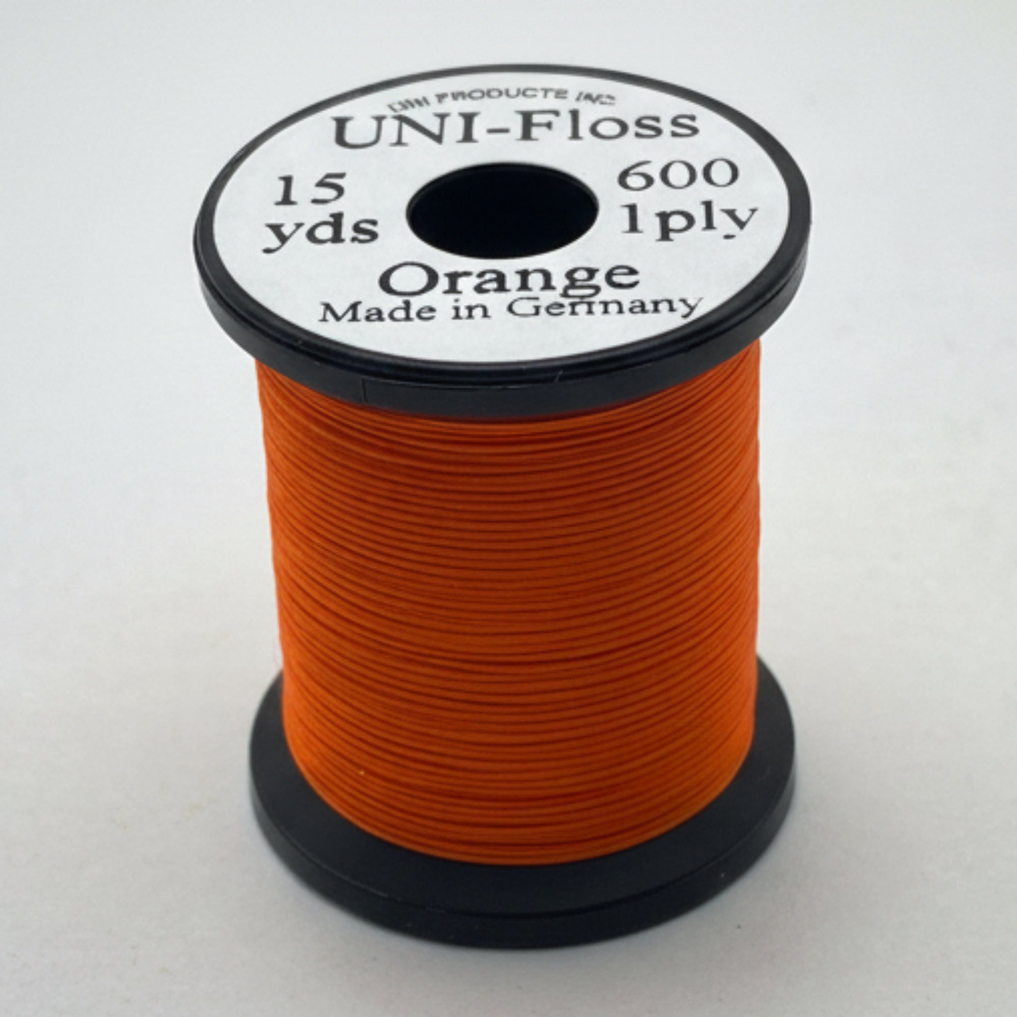 Spool of orange thread with a black and white label on a white background