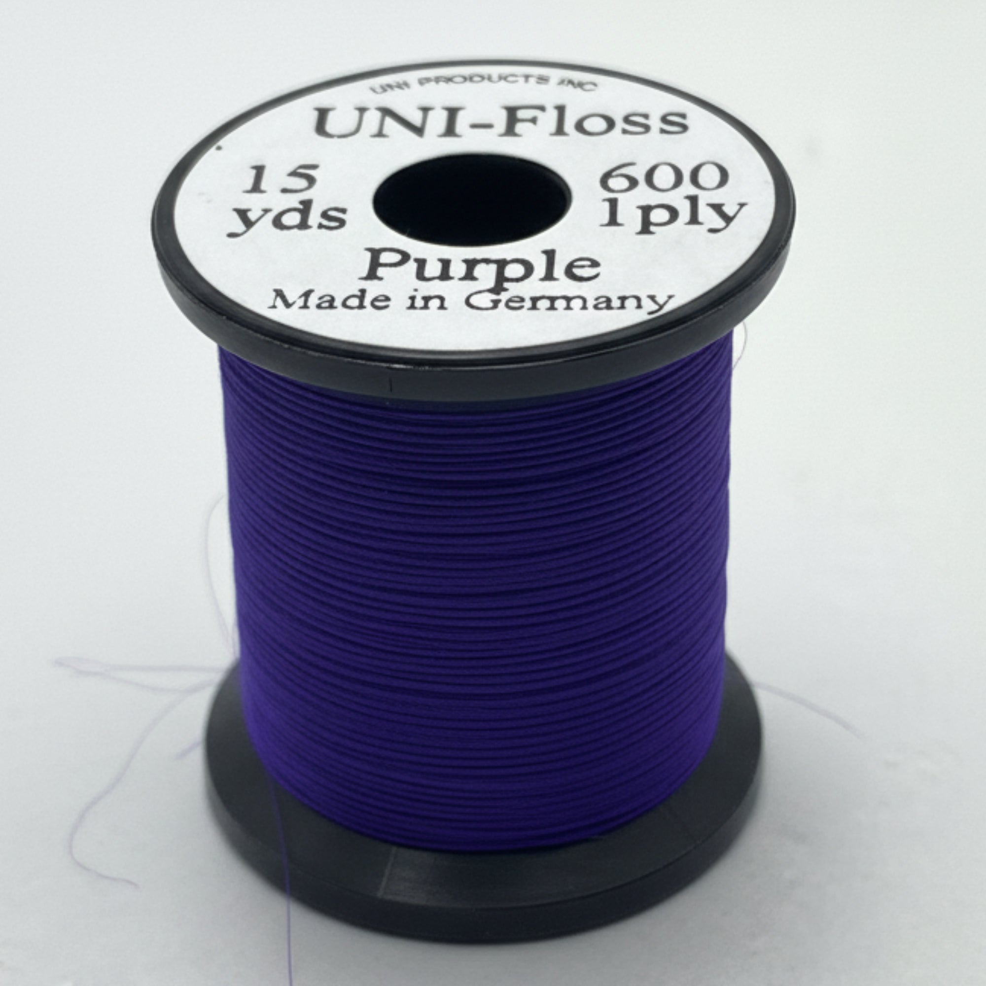 Spool of purple thread with a white label on a light gray background