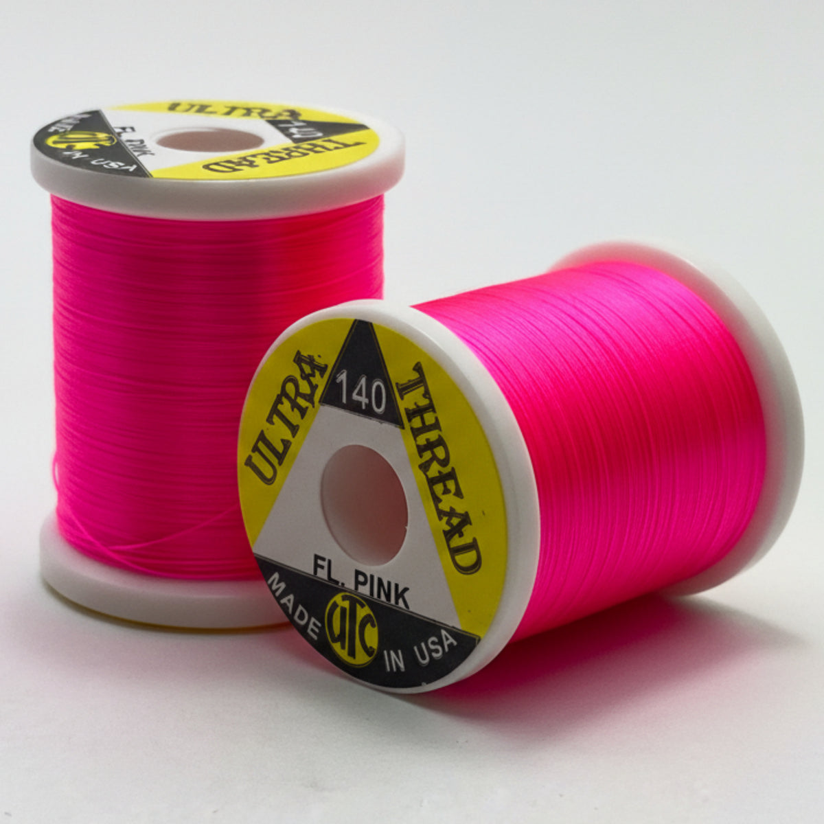 Two spools of pink thread with visible branding on a white background