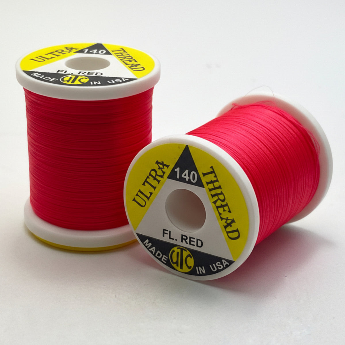 Two spools of red thread with yellow labels on a white background
