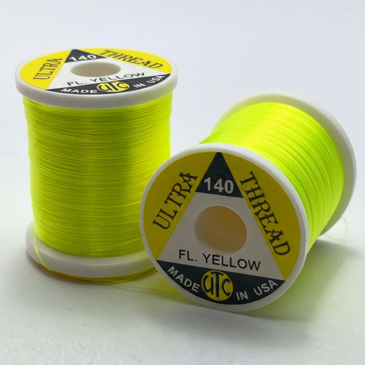 Two spools of yellow thread with visible branding on a white background