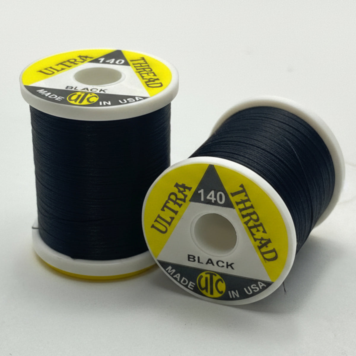 Two spools of black thread on a white background