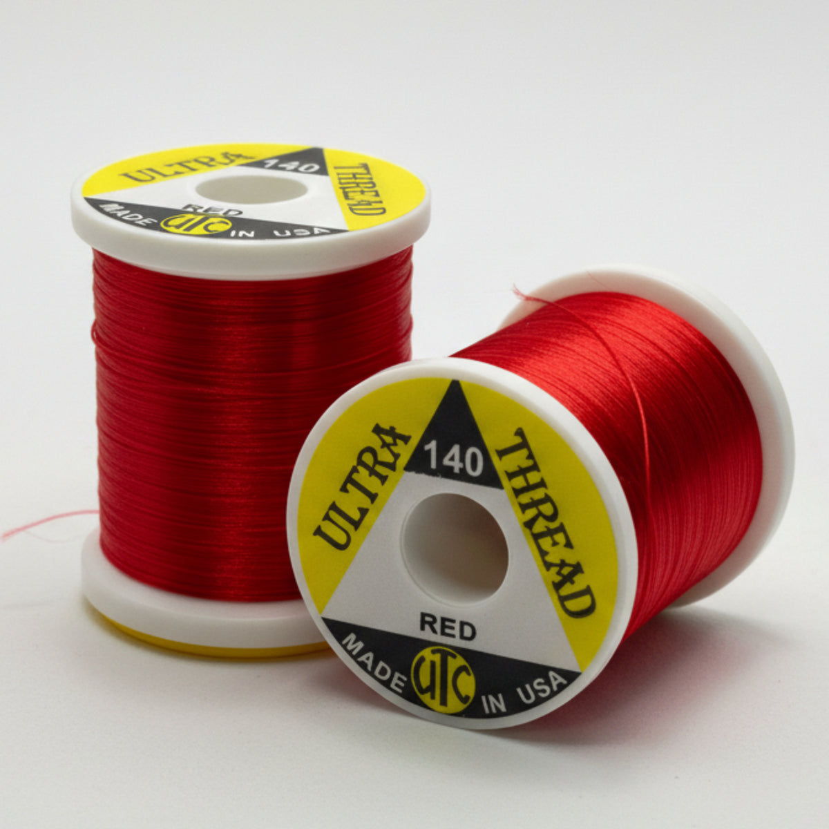 Two spools of red thread with yellow labels on a white background