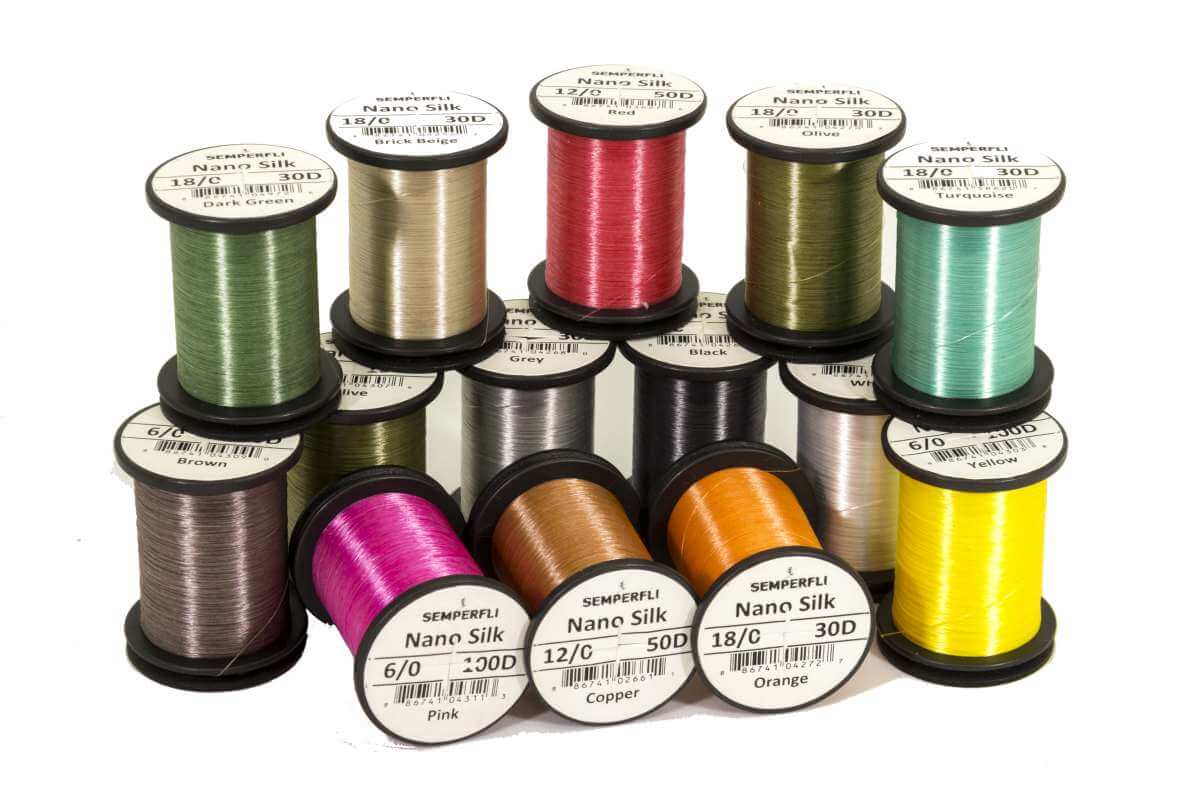 Assortment of spools of Semperfli Nano Silk 6/0 100D Thread in various colors for fly tying.